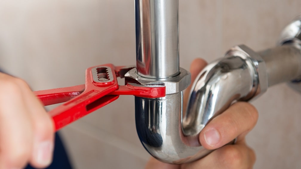 closeup of plumber fixing a pipe with a wrench